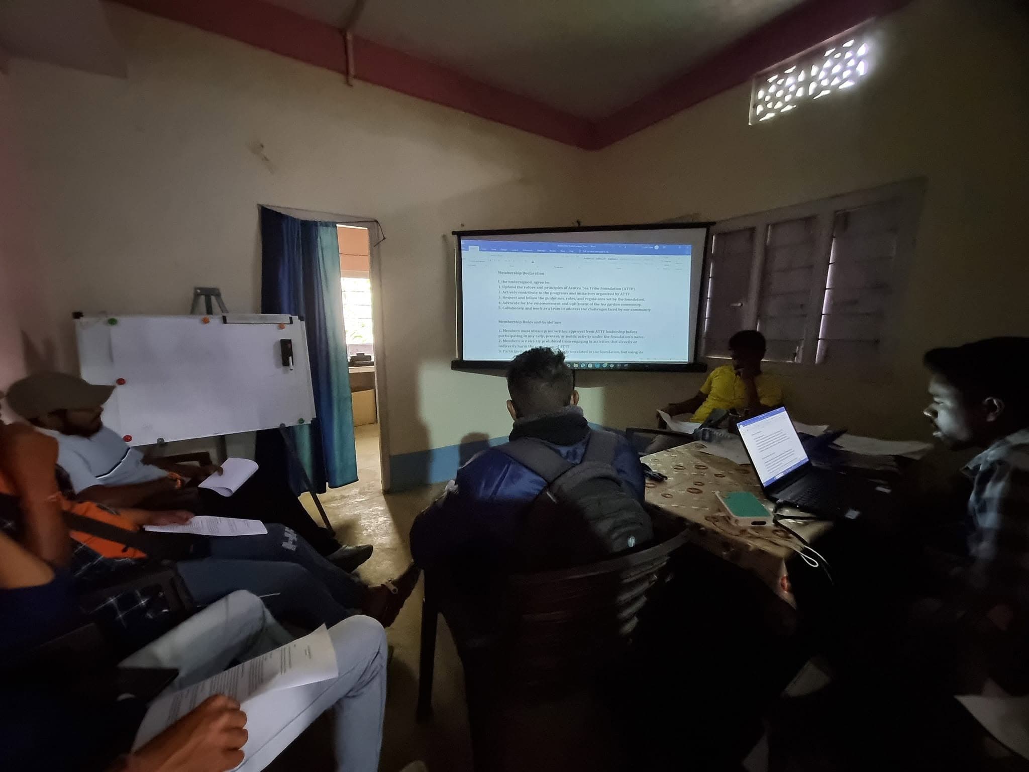 Volunteers seated in front of a projection screen reviewing membership guidelines and rules.