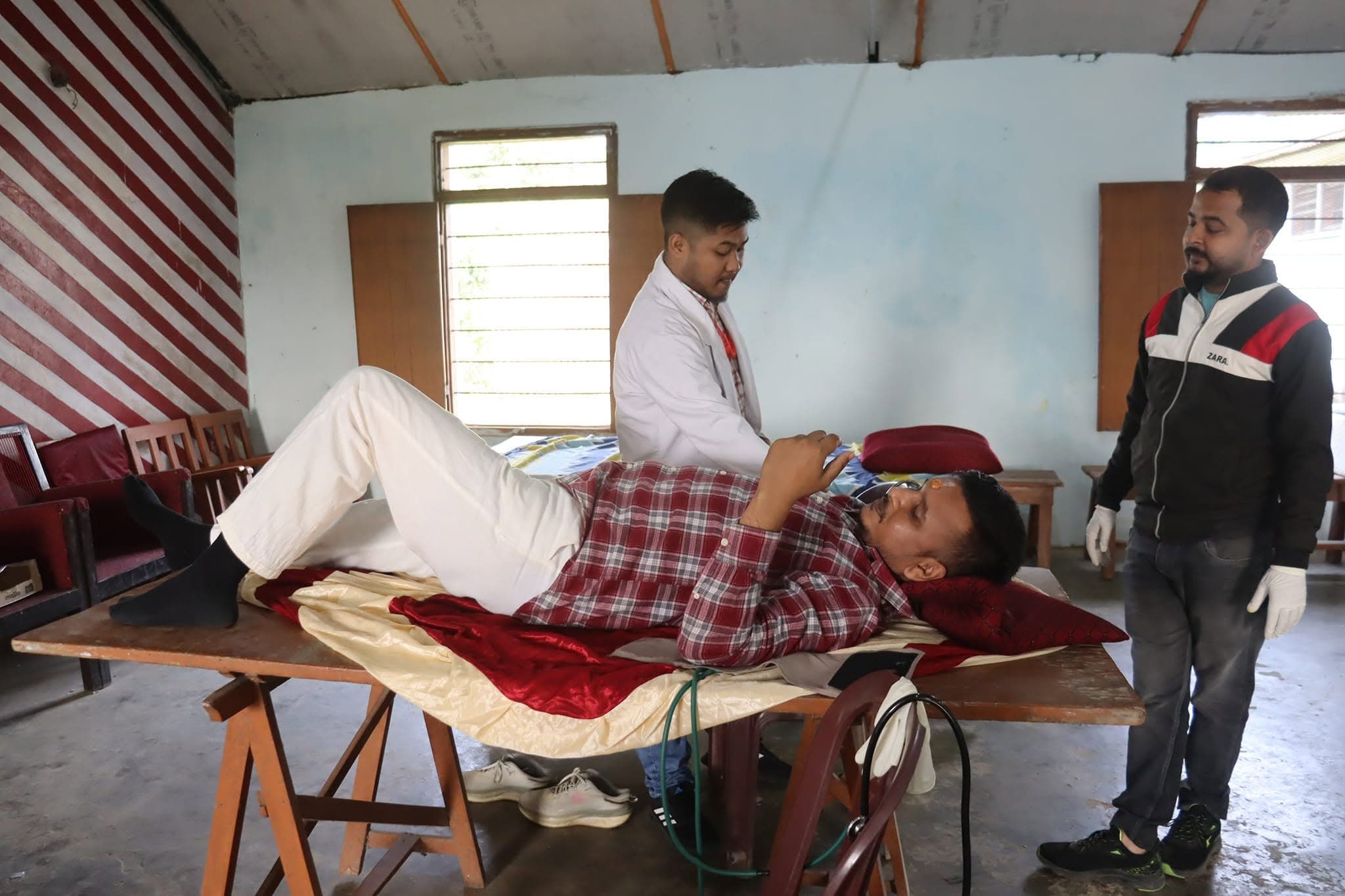 Medical staff monitoring a patient on an examination table during a camp session.