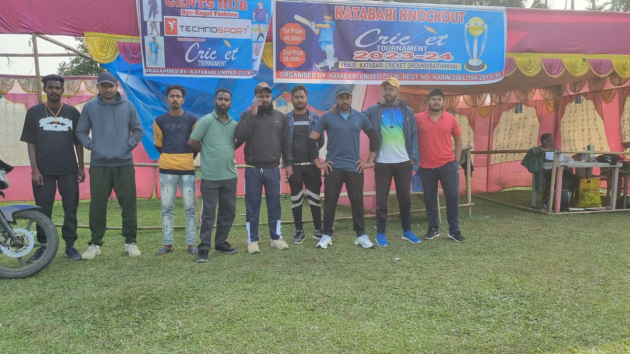 Local community sports tournament banner with organizers and youth standing together.