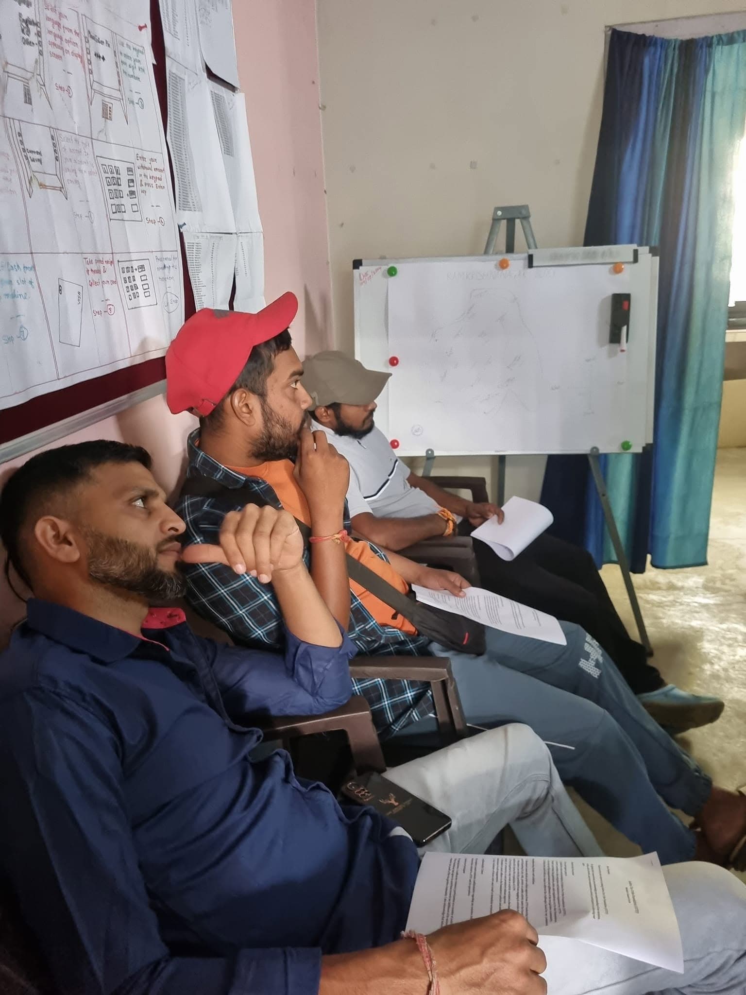 Volunteers in a classroom reviewing strategy diagrams and hand-drawn process charts.