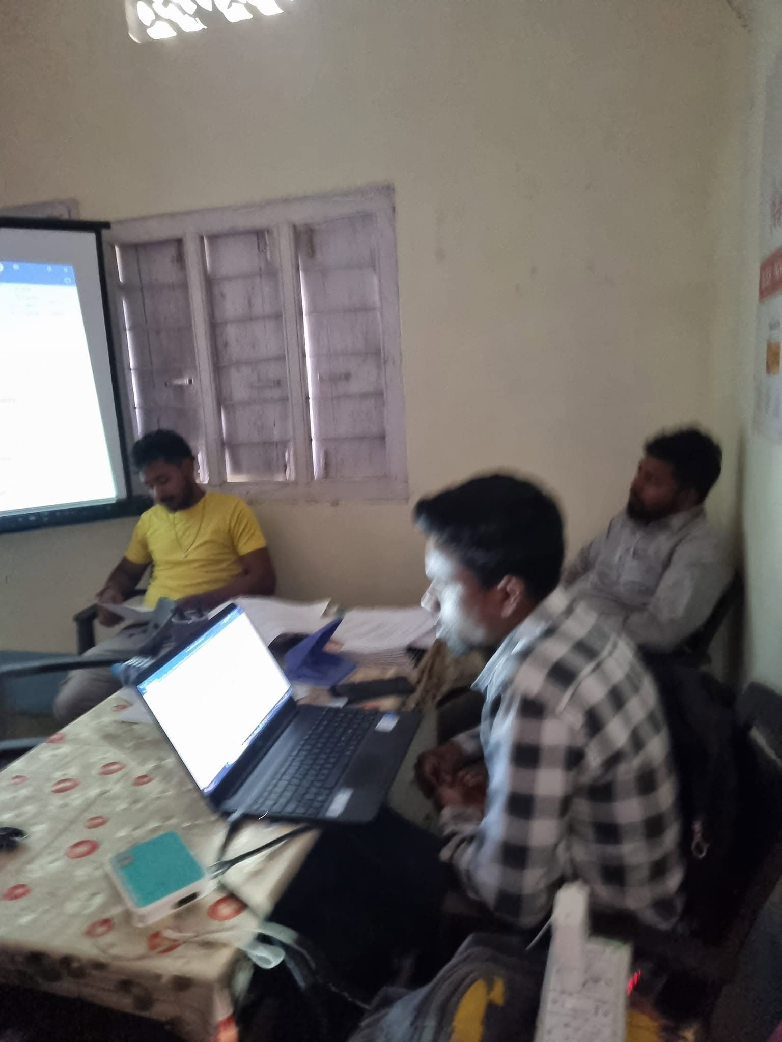 Team coordinator working on laptop during a projected presentation session.