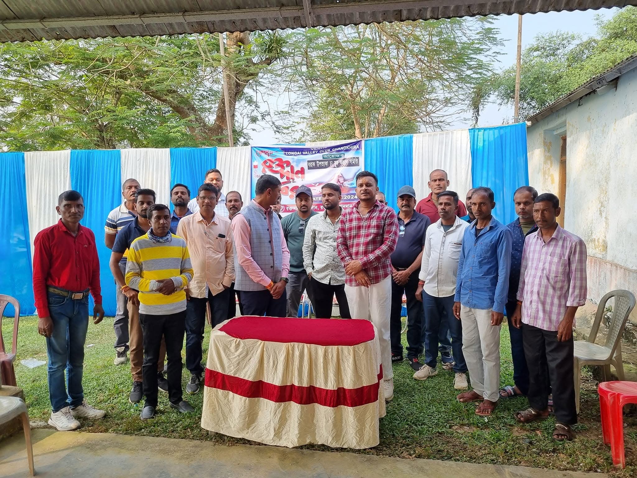 Group of community volunteers gathered in front of a blood donation camp stage.
