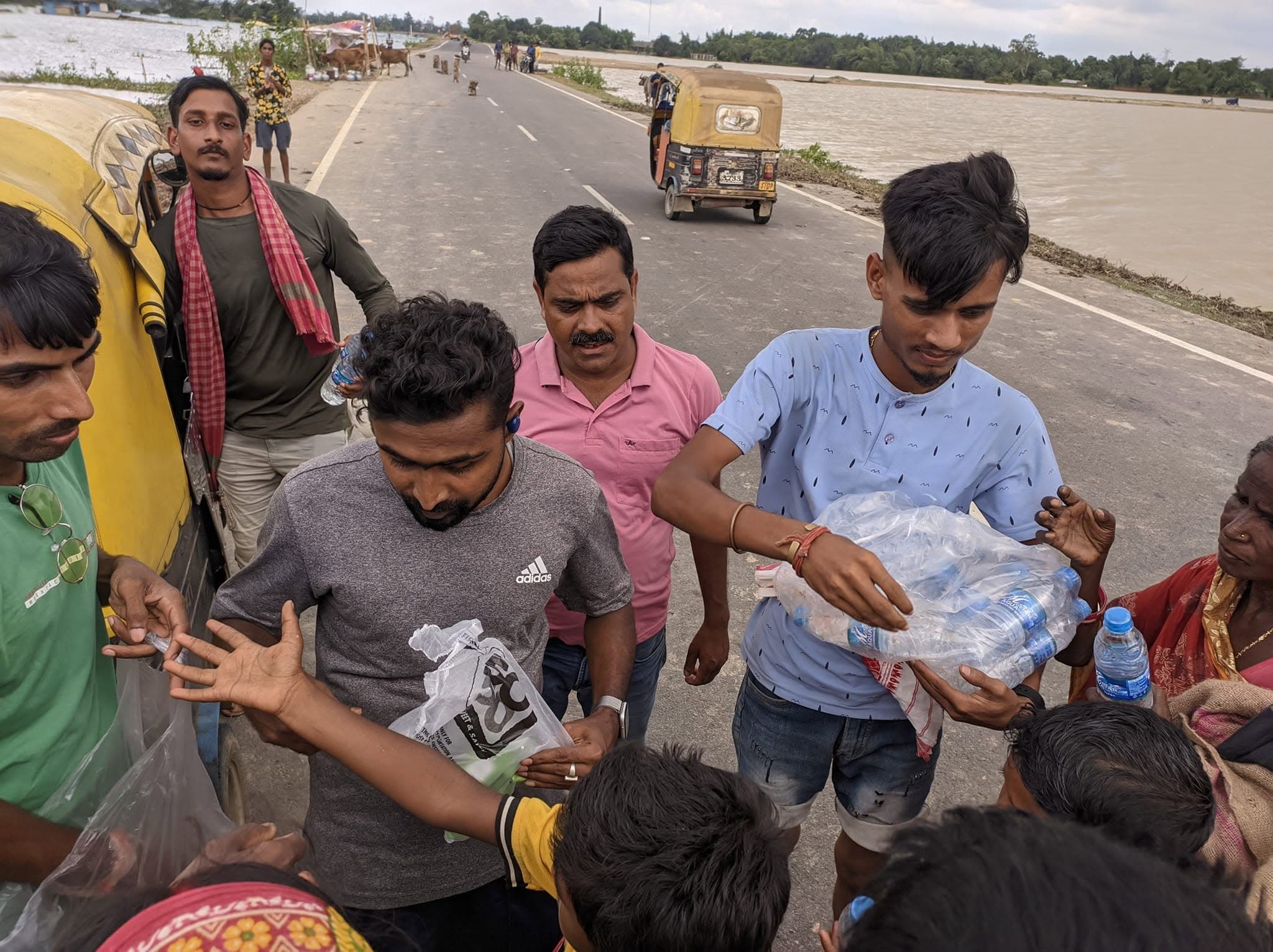 Volunteers providing relief water bottles during flood conditions in Barak Valley.